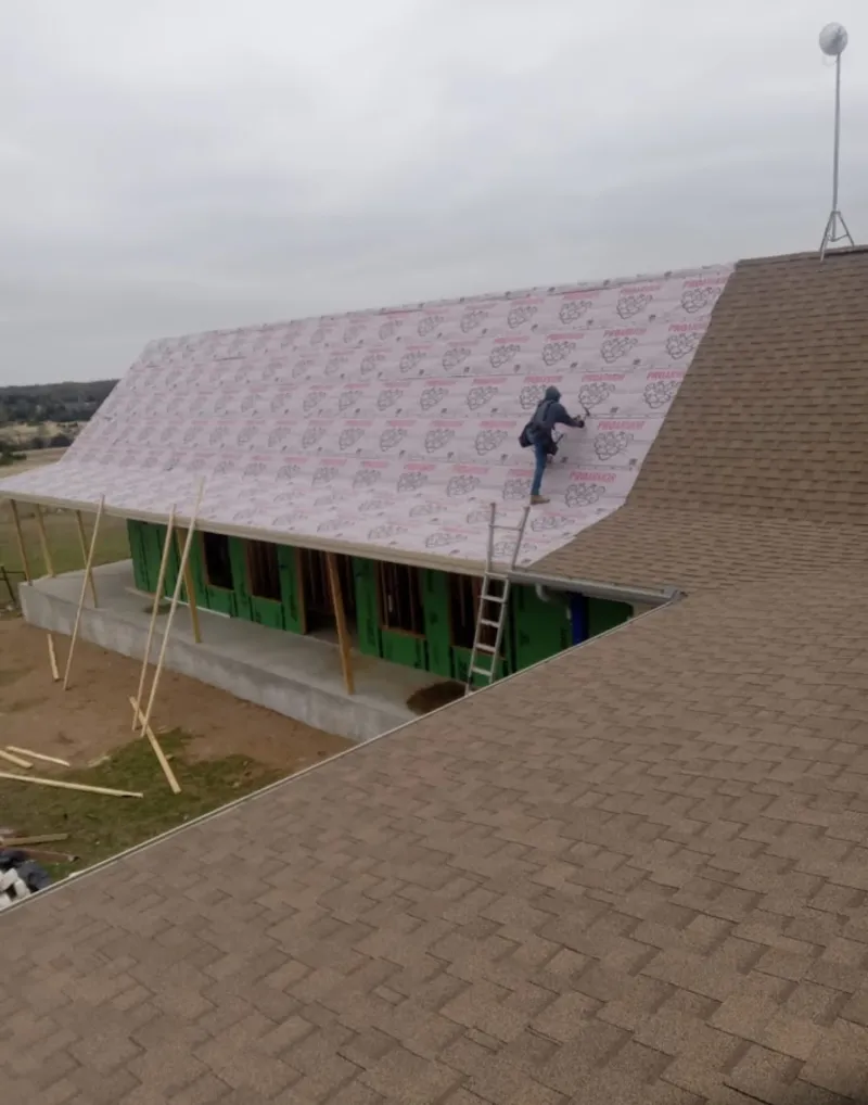 Worker preparing underlayment for a metal roof installation in Maywood